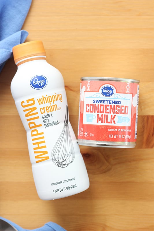 Heavy whipping cream and sweetened condensed milk sitting on a wooden table