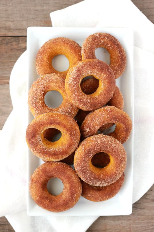 White rectangle plate layered with baked donuts that have been sprinkled with cinnamon and sugar