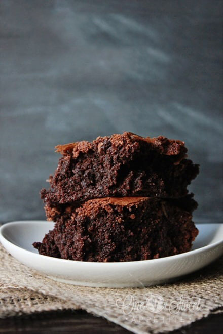 two thick cut brownies stacked on a white plate