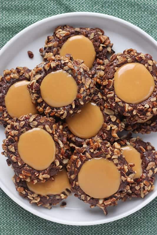 chocolate caramel thumbprint cookies stacked onto a white plate