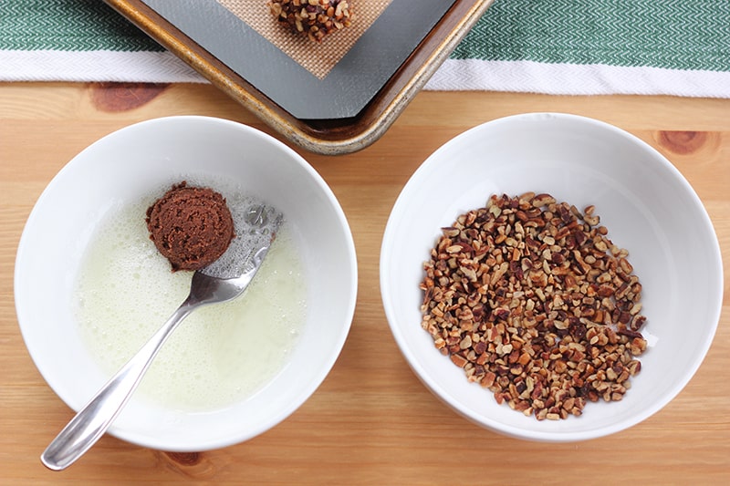 cookie being rolled in an egg white was and rolled in pecans