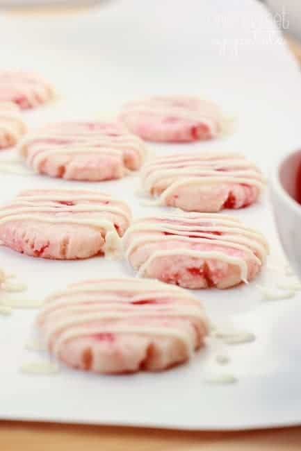 cherry shortbread cookies on a white plate drizzled with chocolate