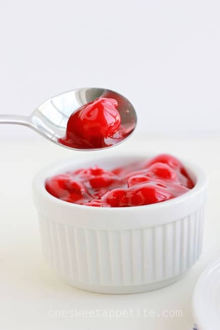 Cherry filling being lifted out of a bowl with a silver spoon.
