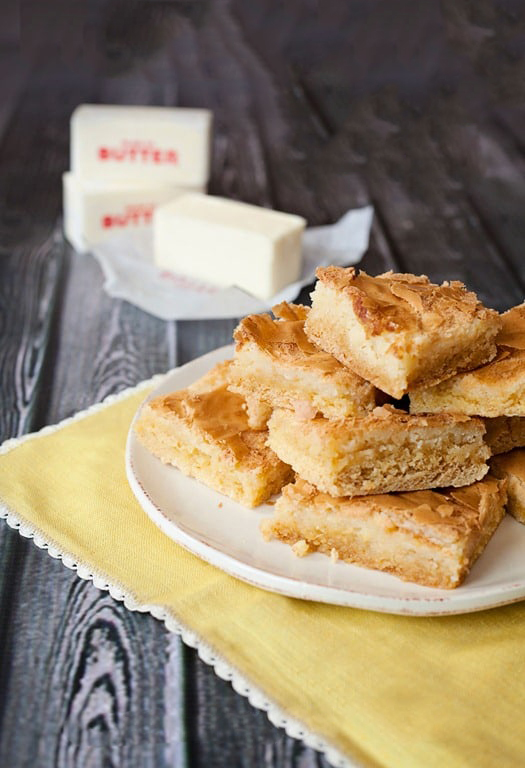 white plate sitting on a yellow napkin stacked with bars, butter sitting in the background