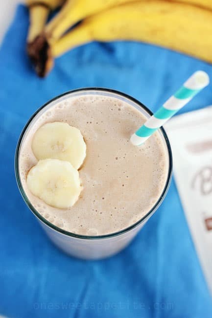 chocolate peanut butter breakfast smoothie in a glass with a stripe straw and sliced bananas