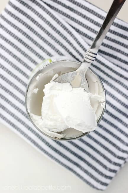 Top down image of coconut milk in a can with a scoop sitting on a spoon