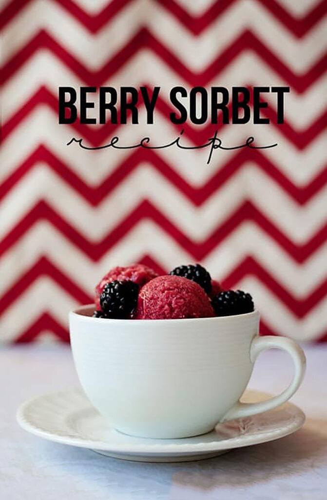 white mug sitting on a saucer filled with scoops of sorbet with fresh blackberries sitting on top