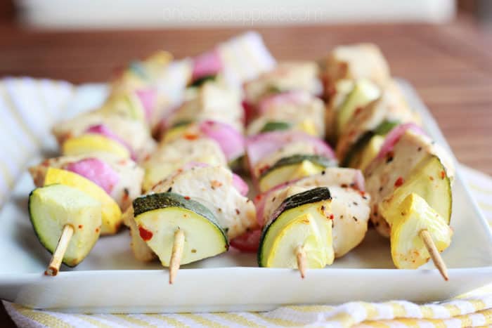 close up image of the end piece of chicken and veggie skewers on a white rectangle plate