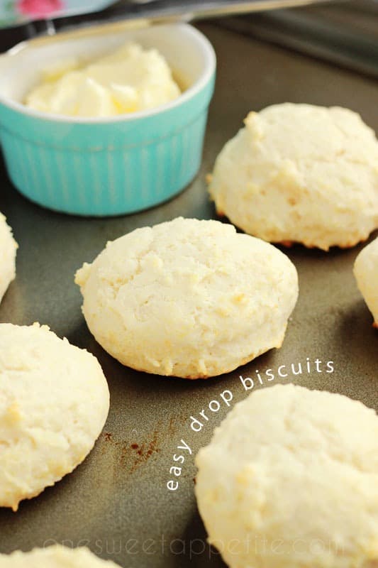 baking tray lined with biscuits and a light blue container of butter with a butter knife 