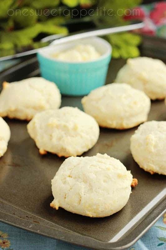 baking tray lined with biscuits and a light blue container of butter with a butter knife 