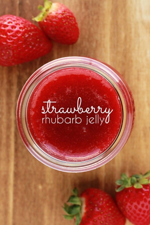 jar of jelly on a wooden cutting board with fresh berries