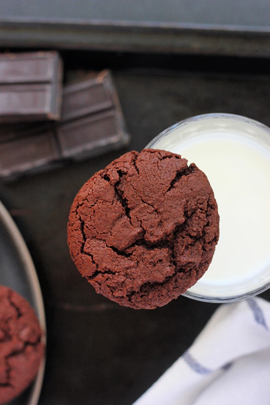 Chocolate cookie balanced on top of a glass of milk