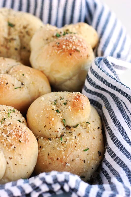 basket lined with a blue and white striped napkin filled with garlic rolls that are tied into a knot