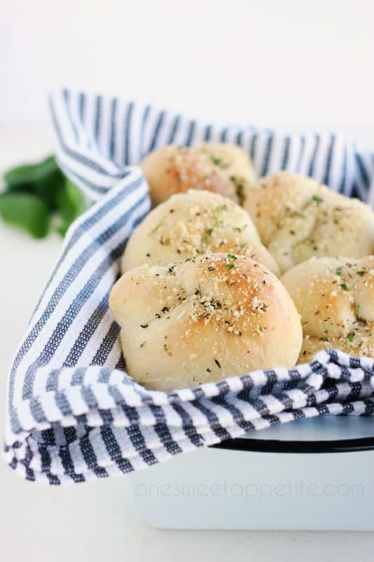 Bread tin filled with garlic rolls on top of a striped napkin