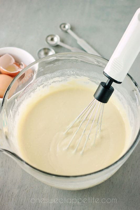 waffle batter in a glass mixing bowl with a whisk