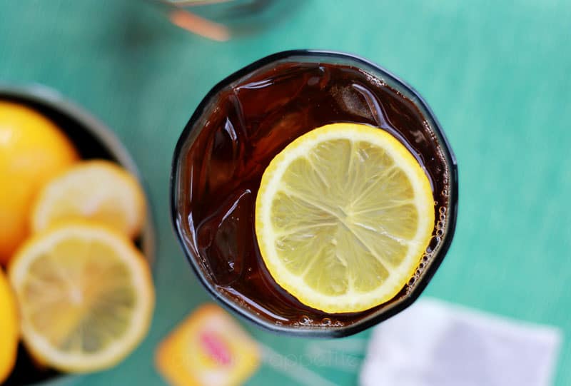 top down image of a glass filled with ice and tea with a lemon slice on a green napkin