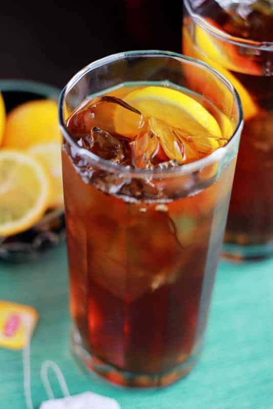 tall glass filled with ice and tea with a lemon slice sitting on a green napkin