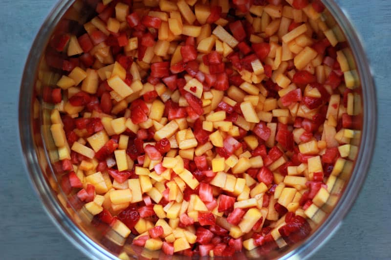 top down image sharing a pot filled with diced strawberries and peaches