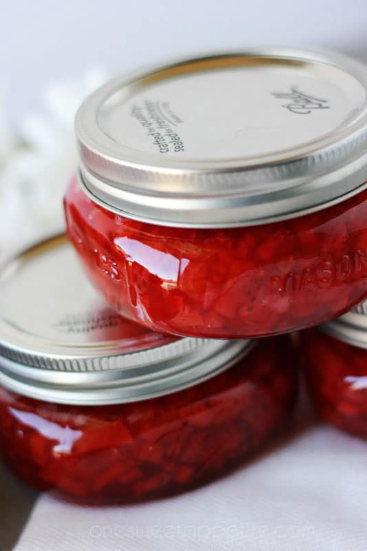 three cans of strawberry jelly stacked on top of each other sitting on a white napkin