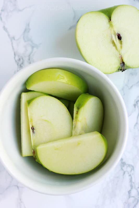 top down image showing a small white bowl filled with green apple slices