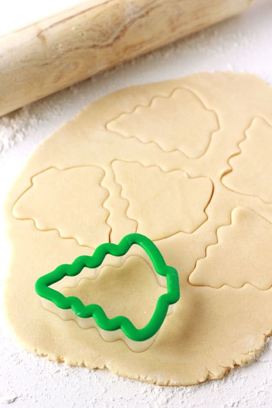 sugar cookie dough rolled out with a chirstmas tree cookie cutter on top