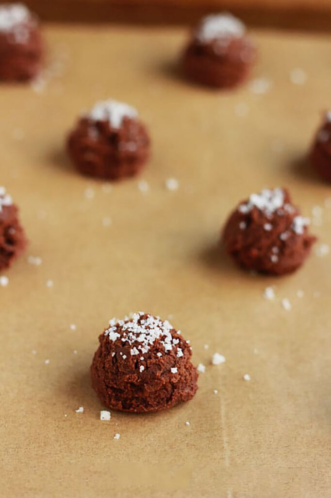 chocolate cookie dough rolled into a ball on a piece of brown parchment sprinkled with salt