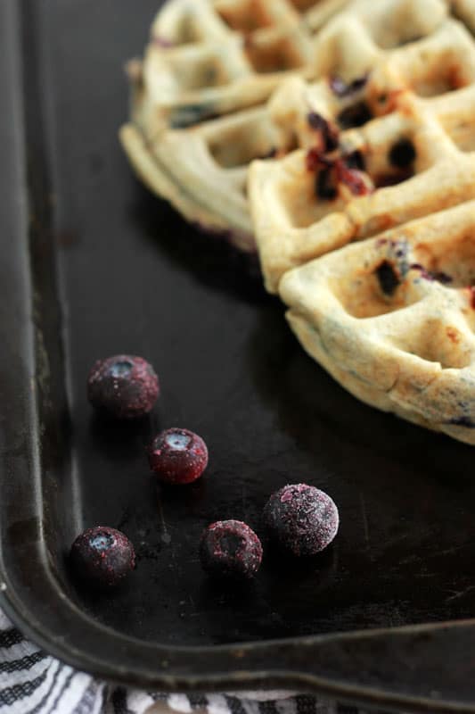 Frozen blueberries on a tray with waffles