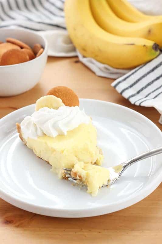 slice of banana cream pie on a white plate with a bite sitting on a fork