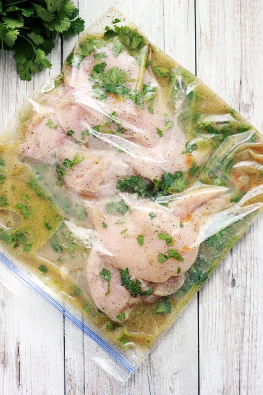 Chicken inside a zip top bag that is filled with marinade. 