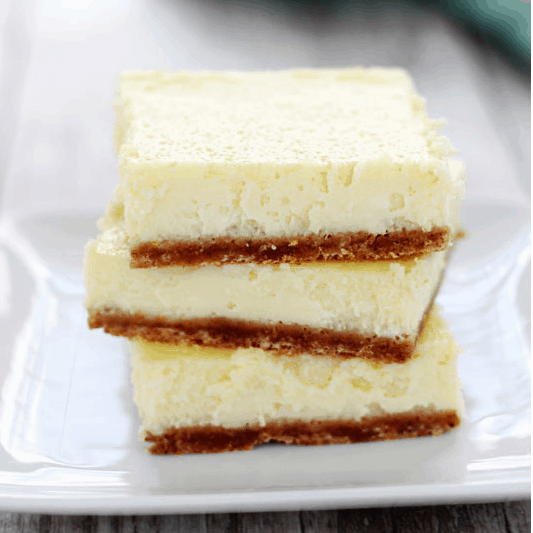 close up of three cheesecake bars stacked on a small white plate