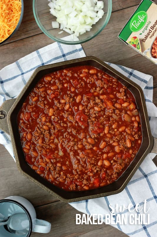 top down image of a cast iron skillet fileld with chili sitting on top of a white and blue stripe napkin