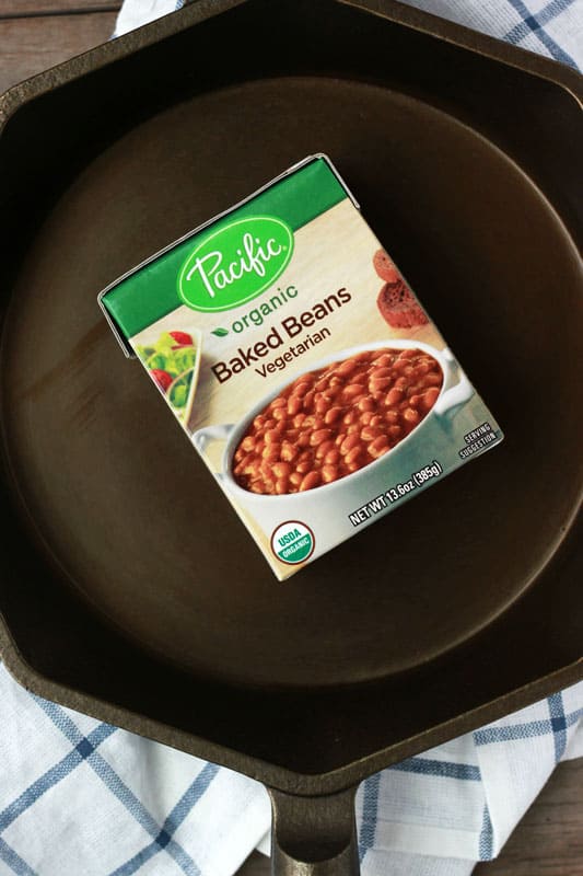 container of baked beans sitting inside a cast iron skillet