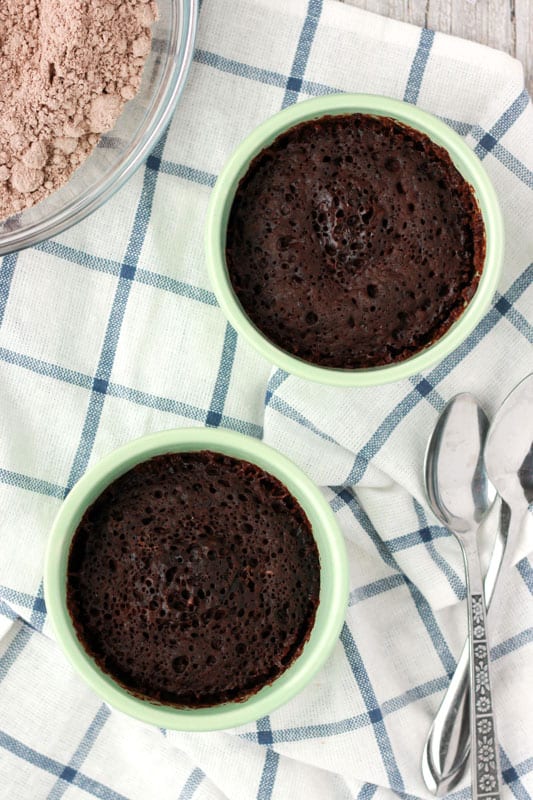 two mint colored ramekins filled with brownies sitting on a white and blue striped napkin