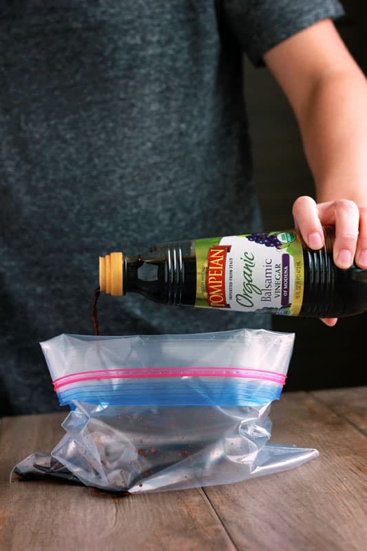 Container of Pompeian balsamic vinegar being poured into a zip top bag