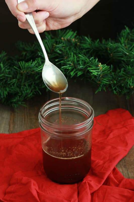 gingerbread syrup on a spoon drizzling into a mason jar