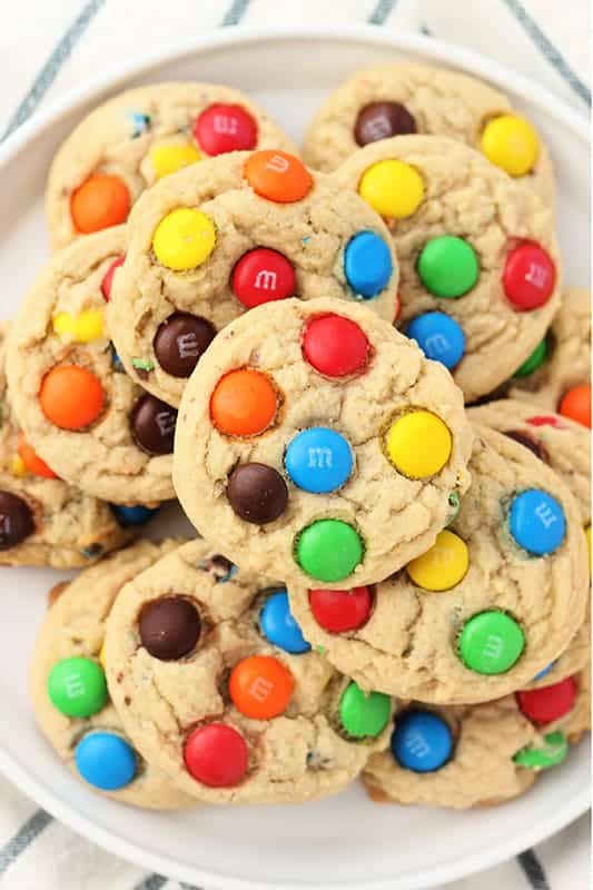 top down close up image of a white round plate that is topped with a pile of cookies that are filled with chocolate coated candies