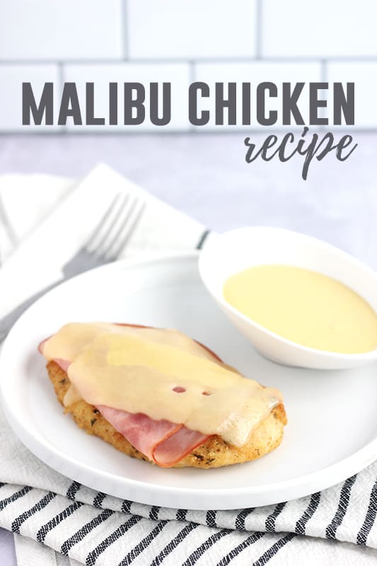 Chicken that has been baked with ham and cheese on top sitting on a white round plate with a small bowl of mustard dipping sauce off to the side. Text overlay reads "malibu chicken recipe"