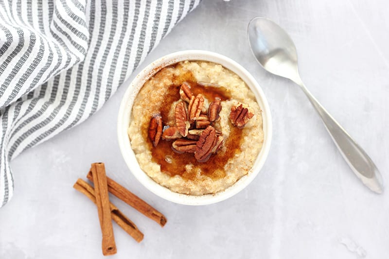 top down image of oatmeal inside of a white dish with cinnamon sticks on the side