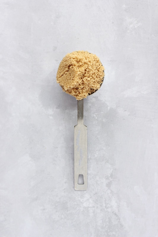 tablespoon filled with brown sugar on a white surface