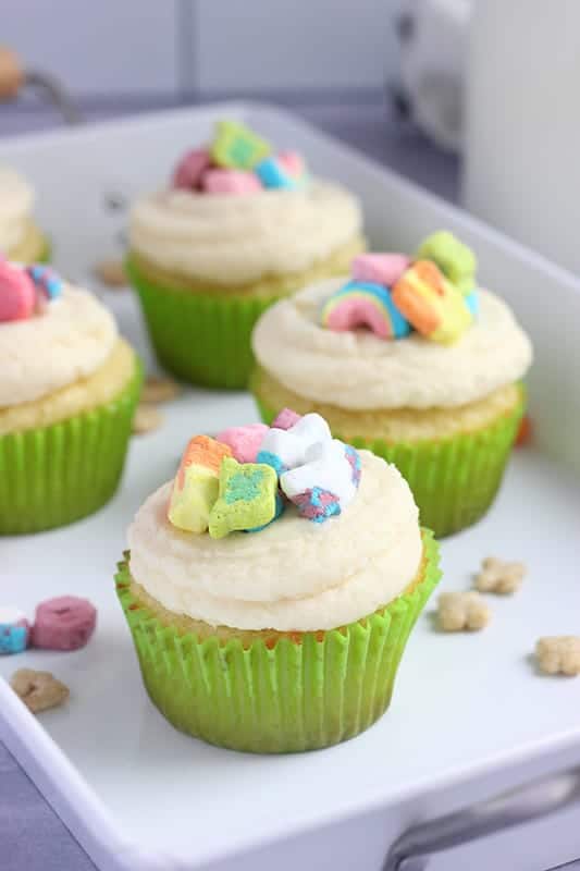 white plate with cupcakes in green liners topped with cereal marshmallows