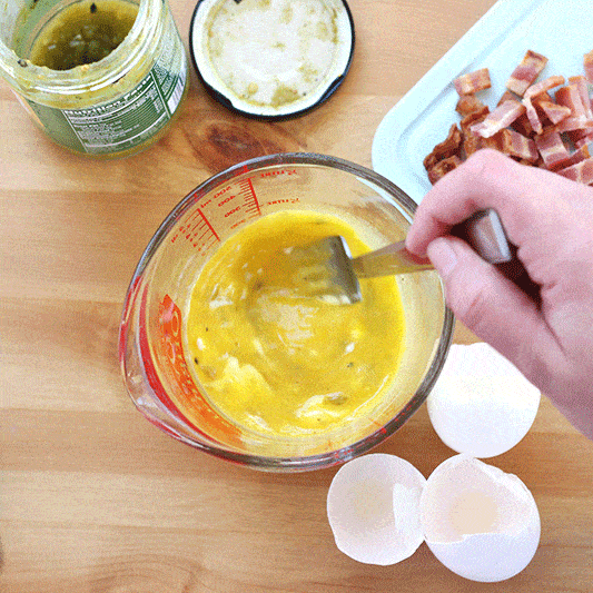 GIF of a glass measuring cup filled with eggs that are being scrambled with a fork