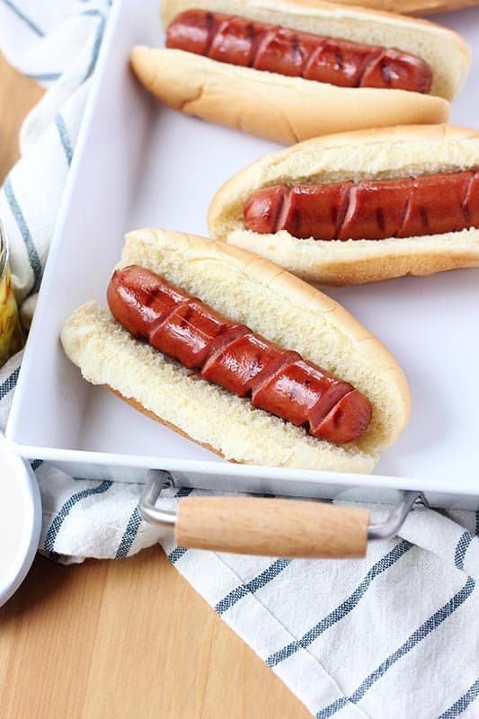 spiral cut hot dogs in buns sitting on a white serving tray