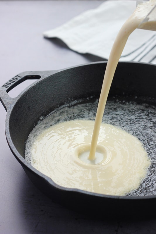 German pancake batter being poured into a hot skillet