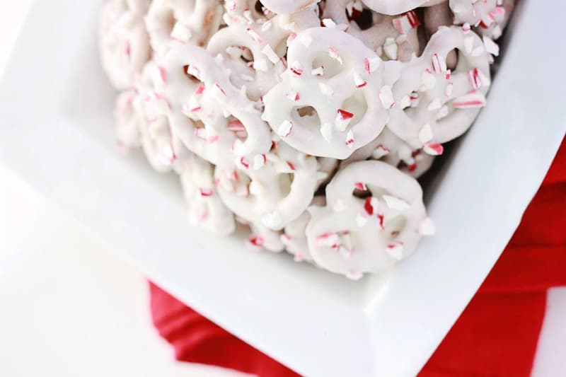 pretzels coated in white chocolate sitting in a white serving dish