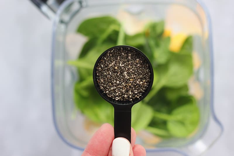 chia seeds in a spoon over blender
