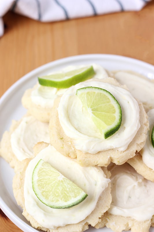 Coconut cookies stacked on a plate with lime slices