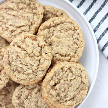 Oatmeal cookies layered on a white plate with a napkin