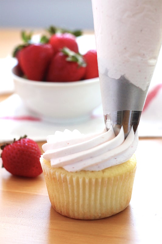 frosting being pipped onto a cupcake