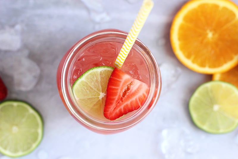 fruit punch in a glass with sliced strawberry and lime