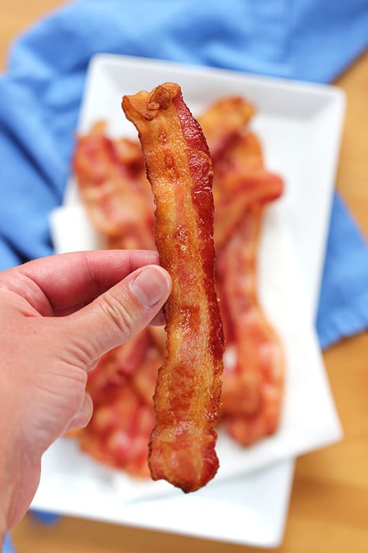 cooked piece of bacon held by hand